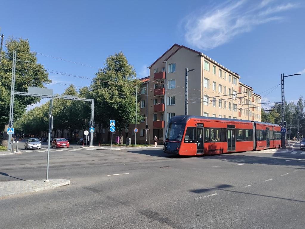 een rode bus rijdt door een stadsstraat bij Apartment Amuri in Tampere