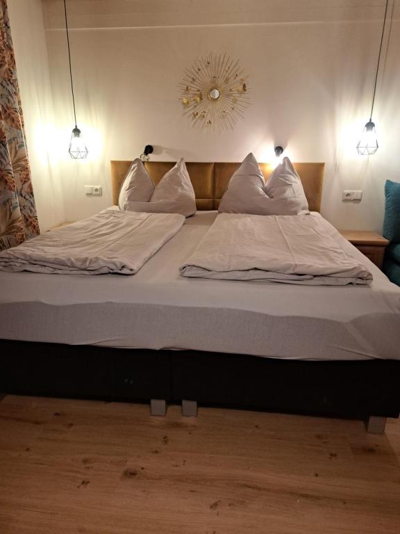 duże łóżko z białą pościelą i poduszkami w obiekcie Ferienwohnung im Grünen w mieście Wolfurt