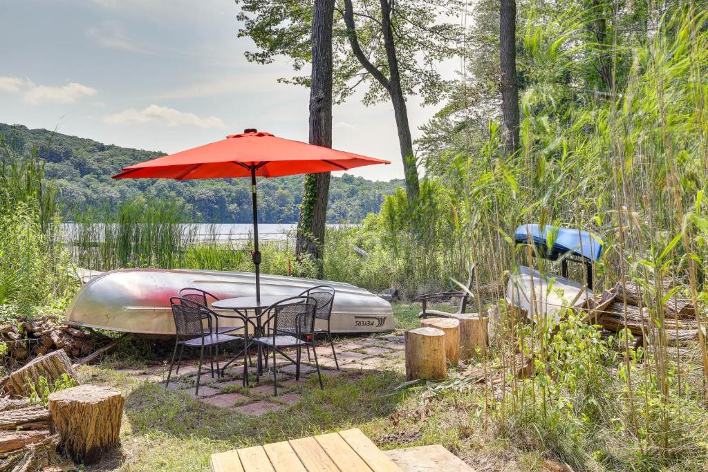 a table with an umbrella next to a boat at Lakefront New York Abode with Deck, Grill and Fire Pit in Mahopac