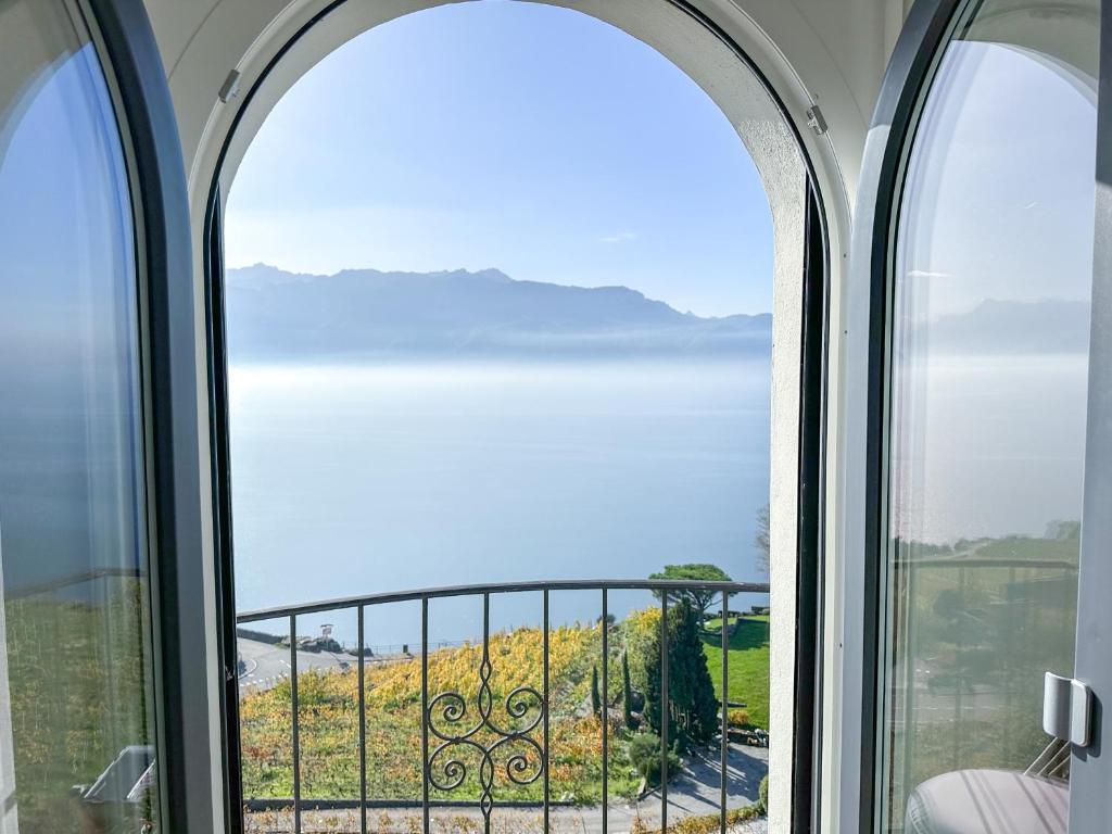 an arched window with a view of the ocean at Room with 360° view overlooking Lake Geneva and Alps in Puidoux