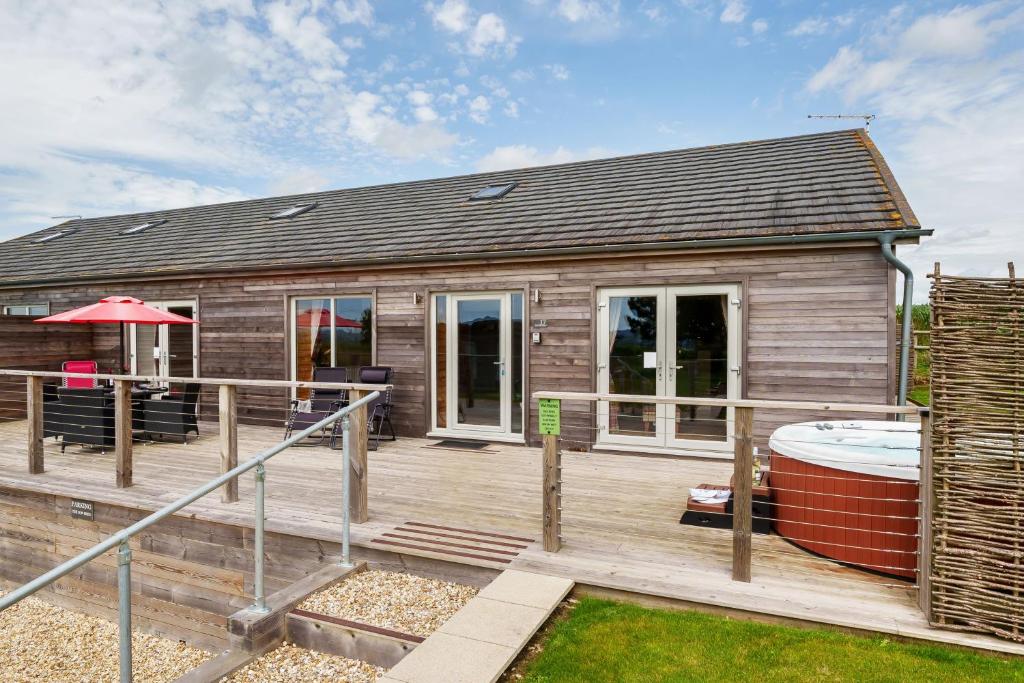 a small house with a deck and a hot tub at The Cow Shed in Sherborne