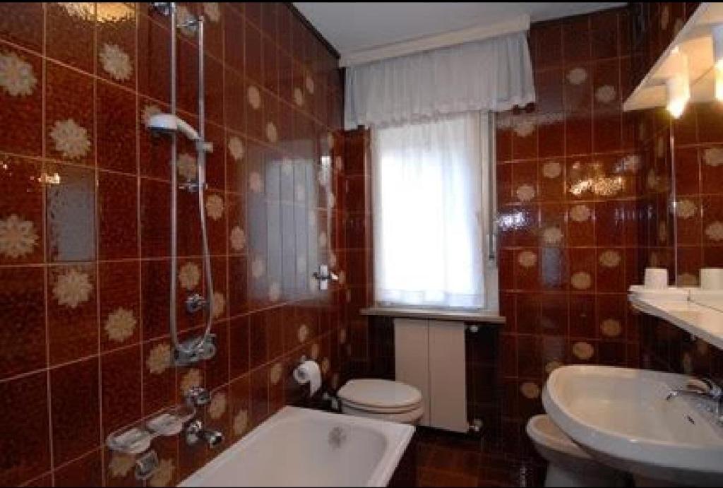 a bathroom with a tub and a toilet and a sink at Big Apartment in Predazzo