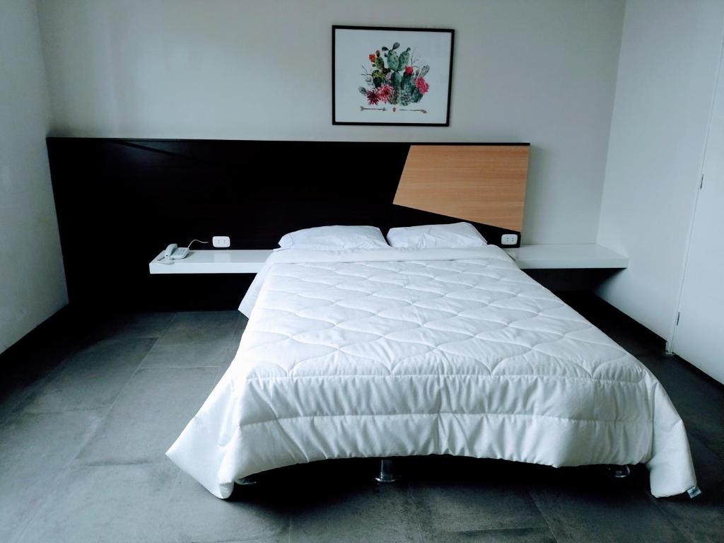 1 dormitorio con cama blanca y cabecero de madera en Hotel Continental, en Barranca