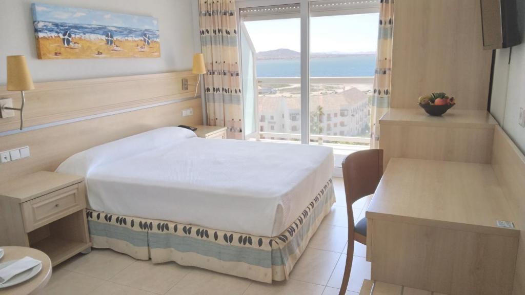Habitación de hotel con cama y ventana en Hotel Las Gaviotas en La Manga del Mar Menor