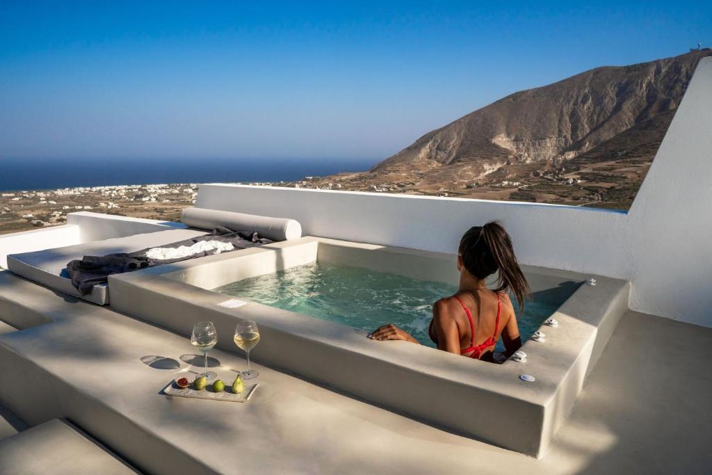 uma mulher sentada numa banheira de hidromassagem numa casa em Wonderful Santorini Villa 1 Bedroom Villa Gonia Astonishing Views and Outdoor Jacuzzi Exo Gonia em Éxo Goniá