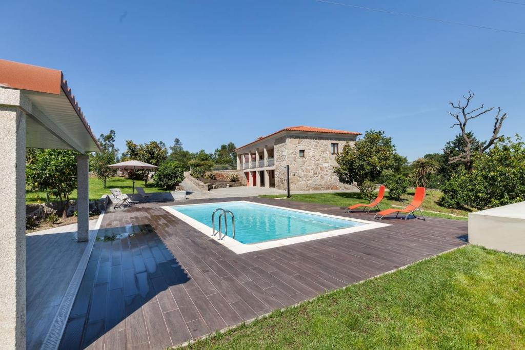 a swimming pool with two chairs and a house at Casa da Tomada - Minho's Guest in Braga