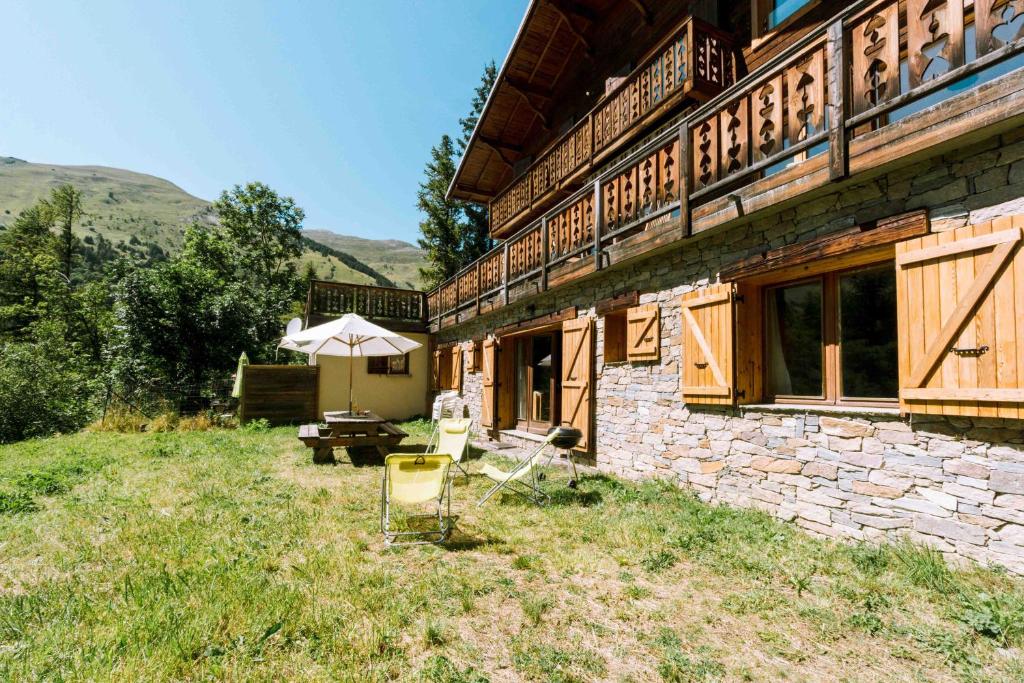 a building with a table and an umbrella in the yard at Appartement dans Chalet 4 étoiles in Valloire