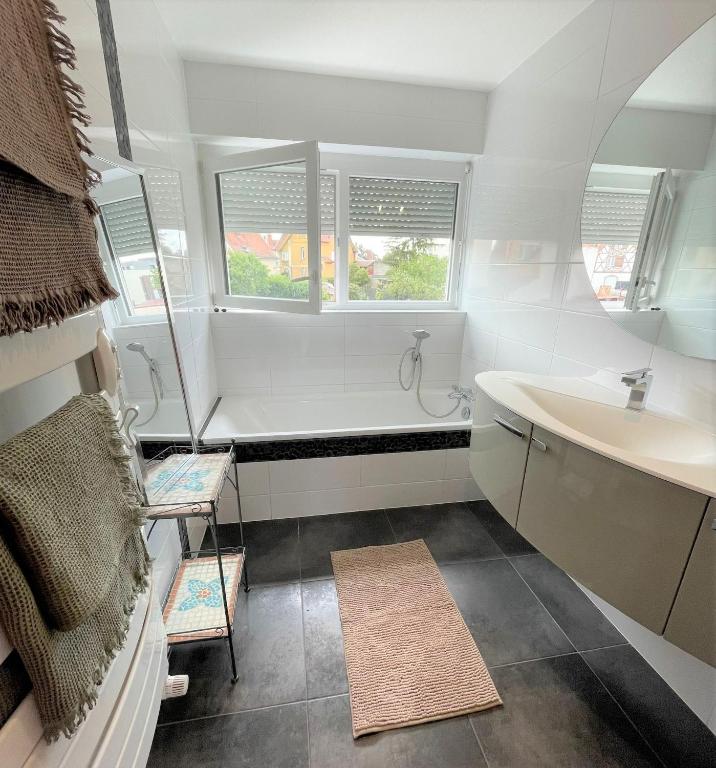 a bathroom with a tub and a sink and two windows at A la villa du voyageur - proche Europa Park, Strasbourg et Colmar in Sélestat
