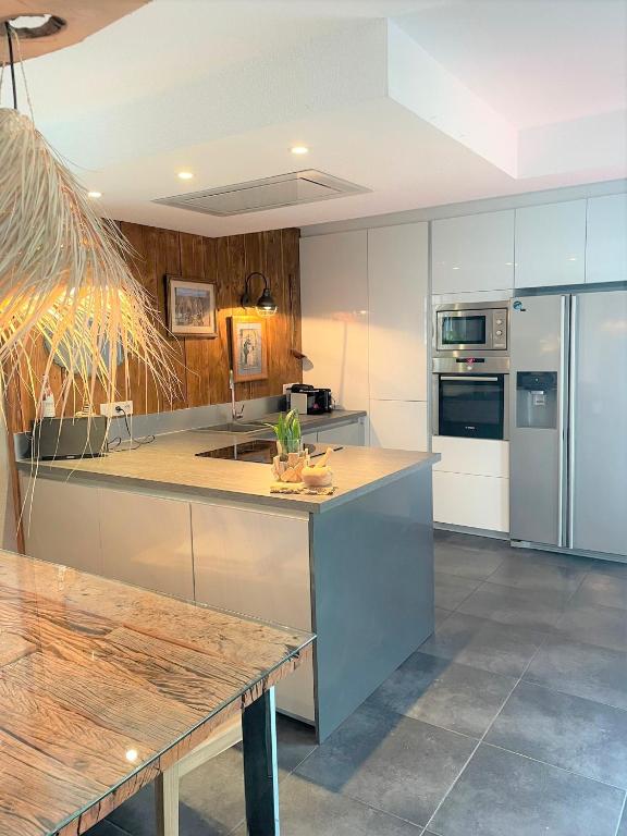 a kitchen with stainless steel appliances and a wooden table at A la villa du voyageur - proche Europa Park, Strasbourg et Colmar in Sélestat