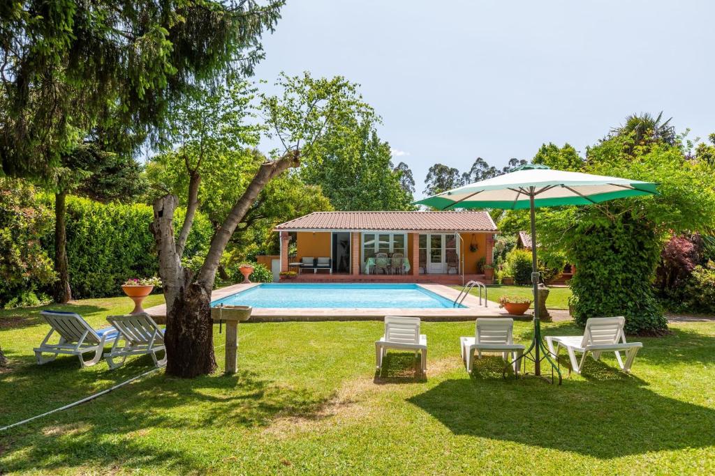 - Piscina con sillas, mesa y sombrilla en Casa do Monte - Minho's Guest en Cabanelas