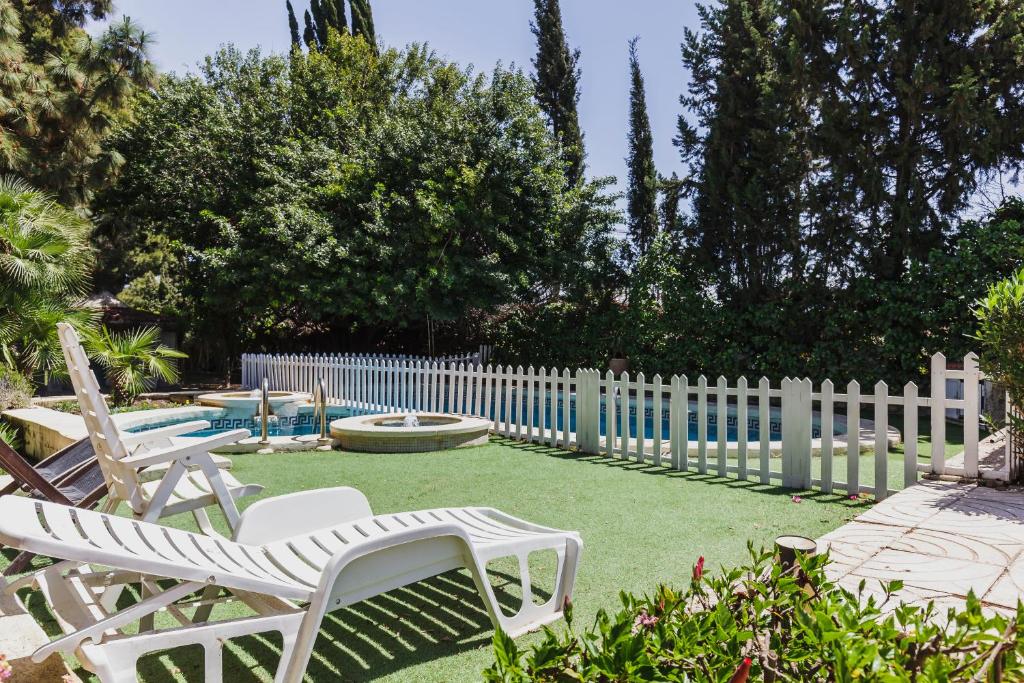 un patio trasero con sillas blancas y una valla en CORTIJO EL LLANO GRAND, en Almería
