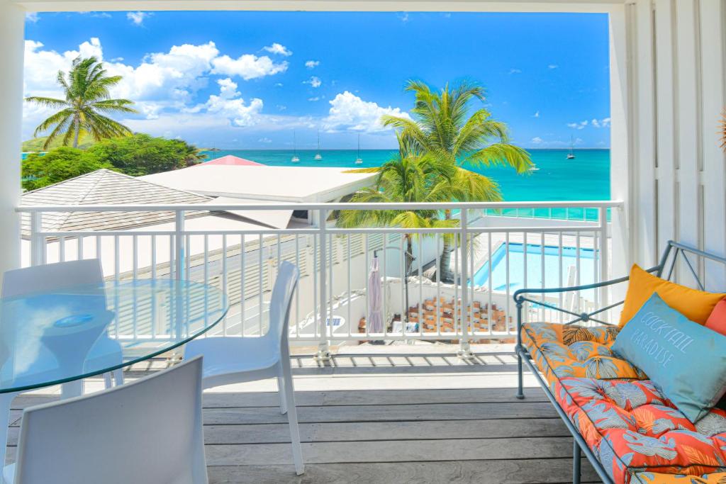 a balcony with a couch and a view of the ocean at Kokonut Sea view Beach Front Pool Central Garage in Grand Case