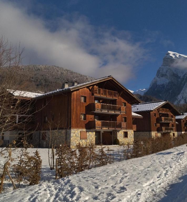 un bâtiment dans la neige avec une montagne en arrière-plan dans l'établissement Chardons Argentés, à Samoëns