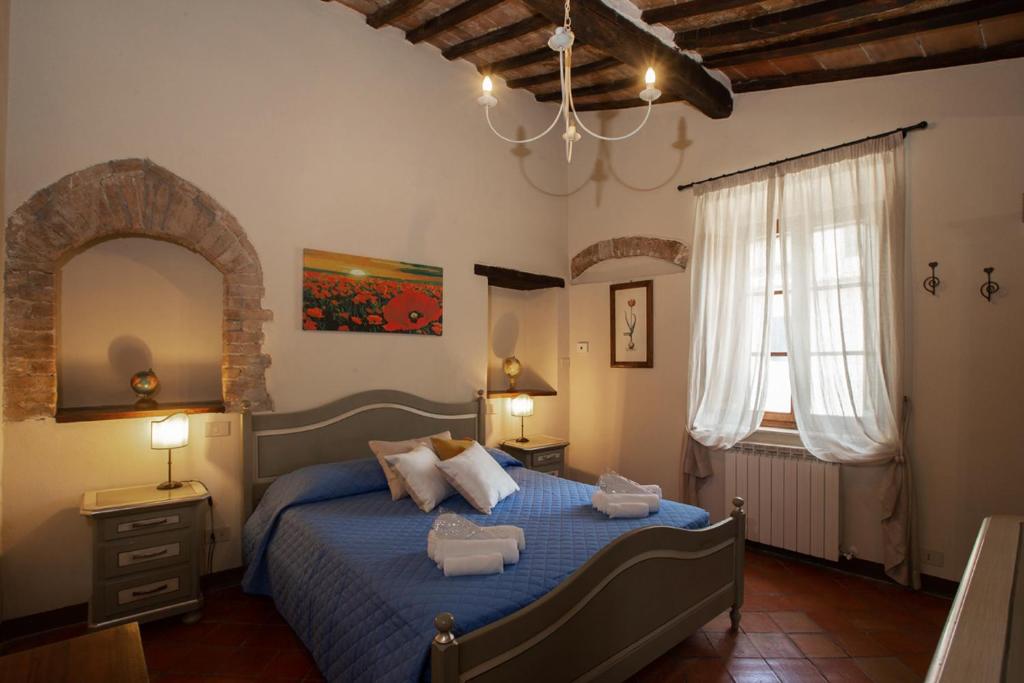 a bedroom with a bed with blue sheets and a window at Locanda Il Porcellum in Bagno Vignoni