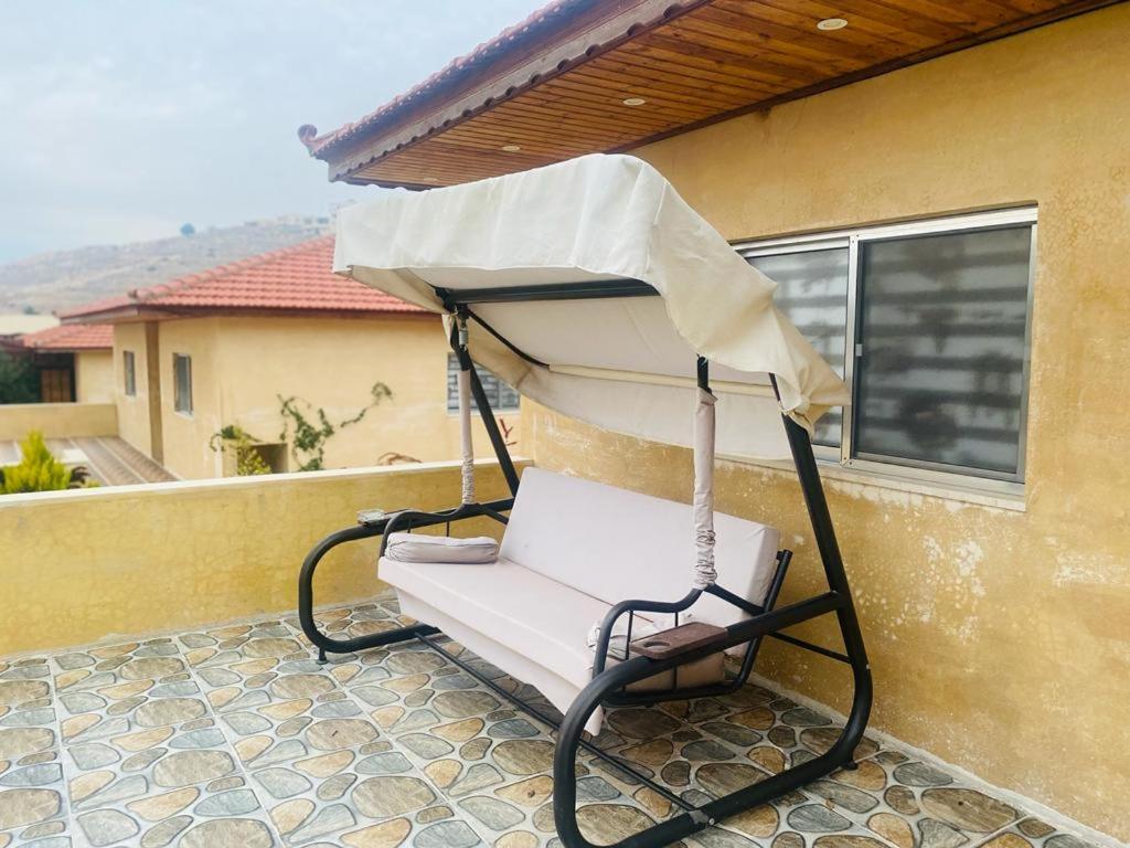 a swinging chair with an umbrella on a porch at North Jewel 2023 in Ajloun