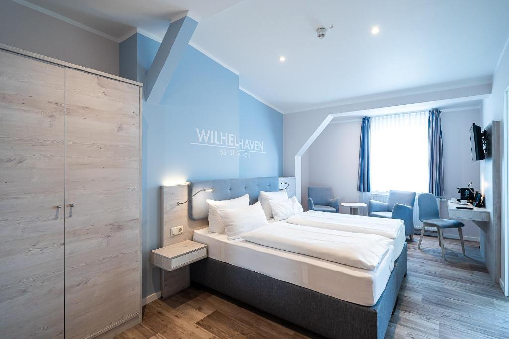 a bedroom with a large bed and a desk at Wilhelms HAVEN HOTEL in Wilhelmshaven