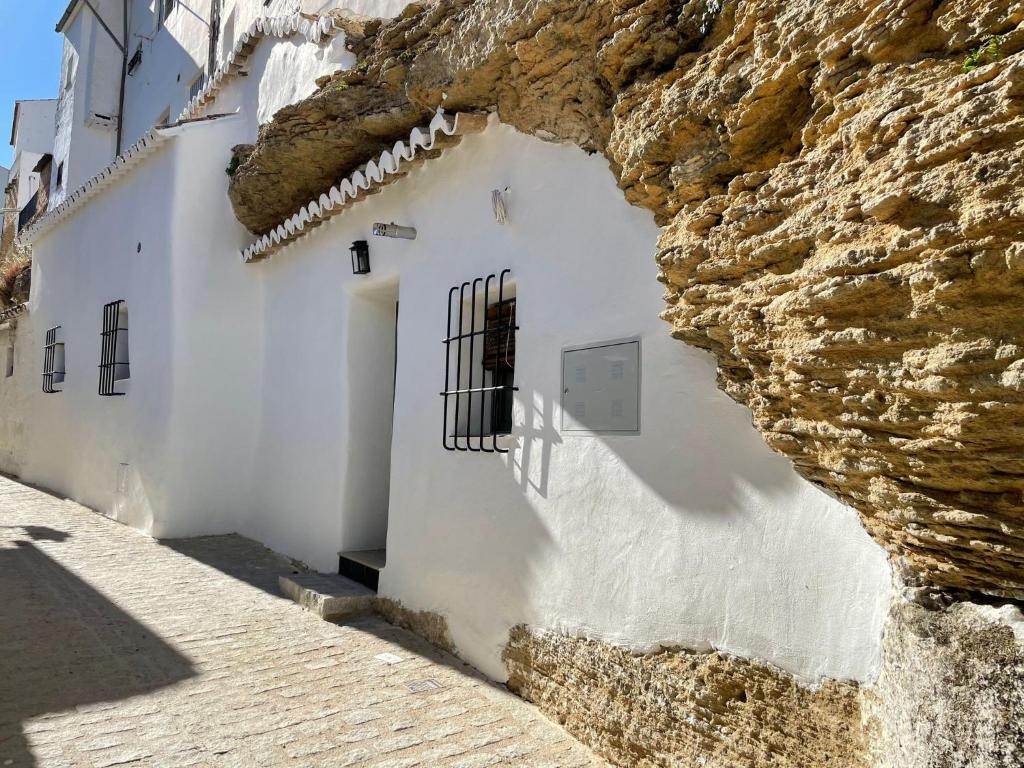 ein weißes Gebäude neben einer Steinmauer in der Unterkunft Tajito Romano in Setenil de las Bodegas