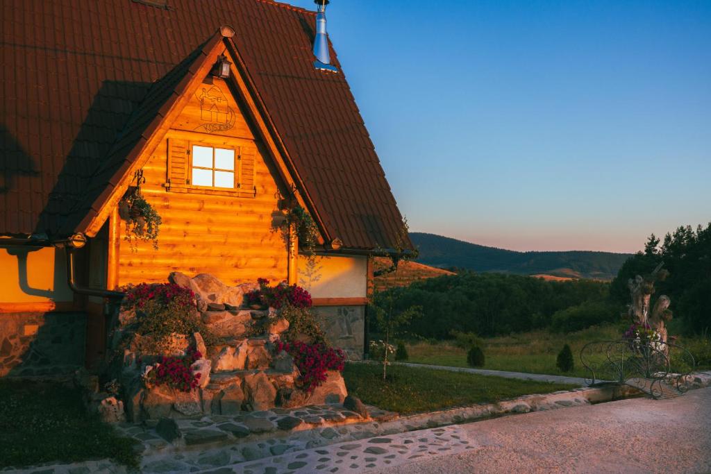 a wooden house with flowers in front of it at Mountain House Kosjenka in Kupres