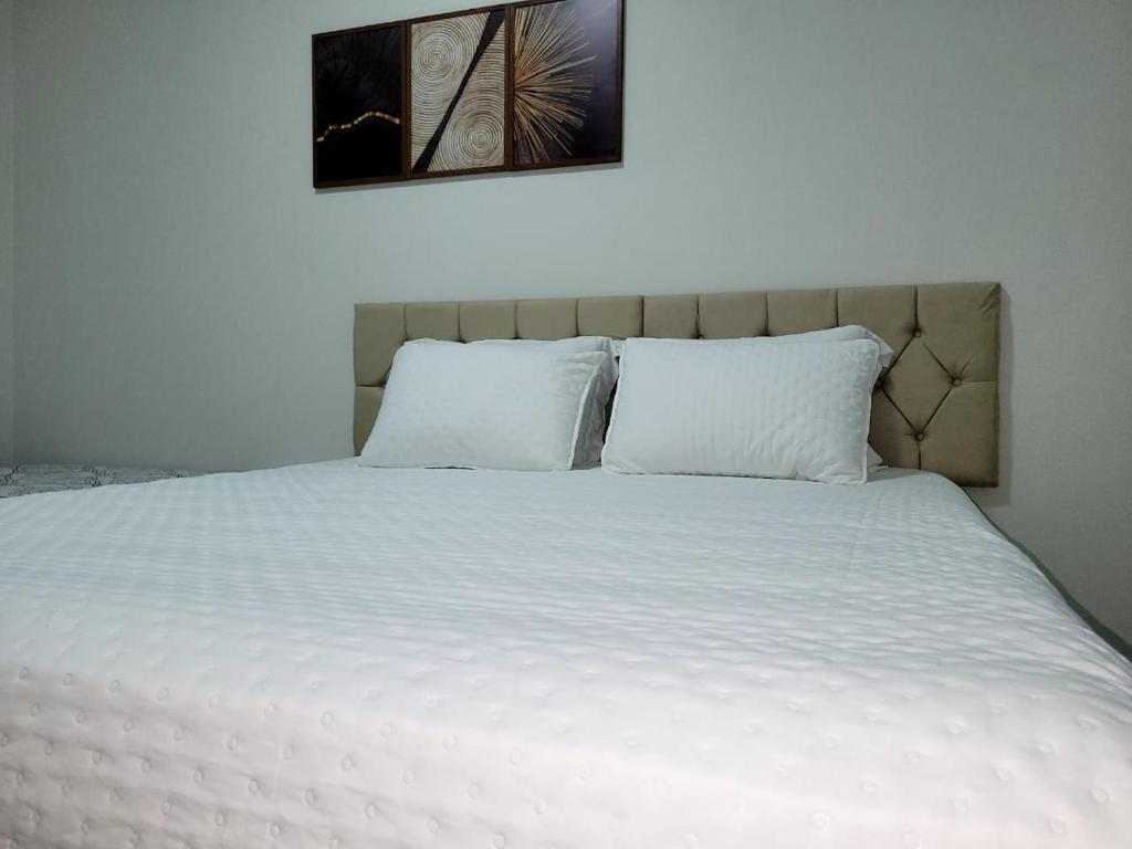 a bed with white sheets and pillows in a bedroom at Madeira Lofts - Suite 01 in Juína