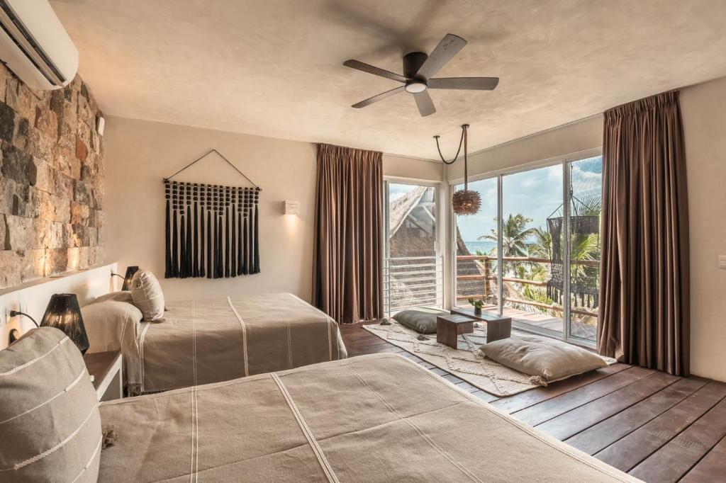 een slaapkamer met 2 bedden en een plafondventilator bij Niken Beachfront Tulum Hotel in Tulum