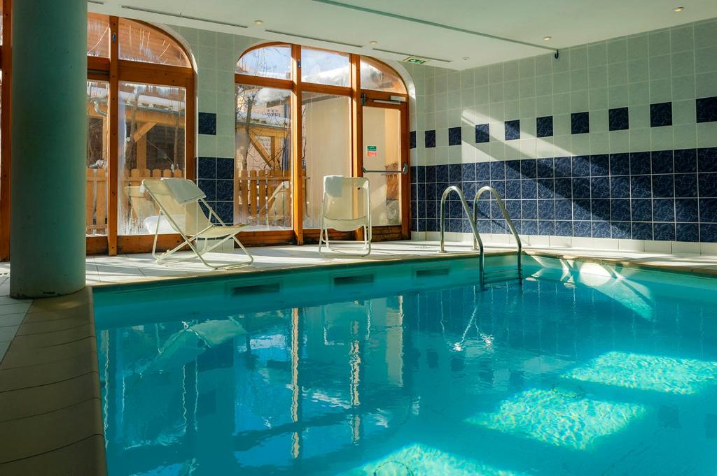 a swimming pool with two chairs in a house at Résidence Goélia Le Blanchot in Pralognan-la-Vanoise
