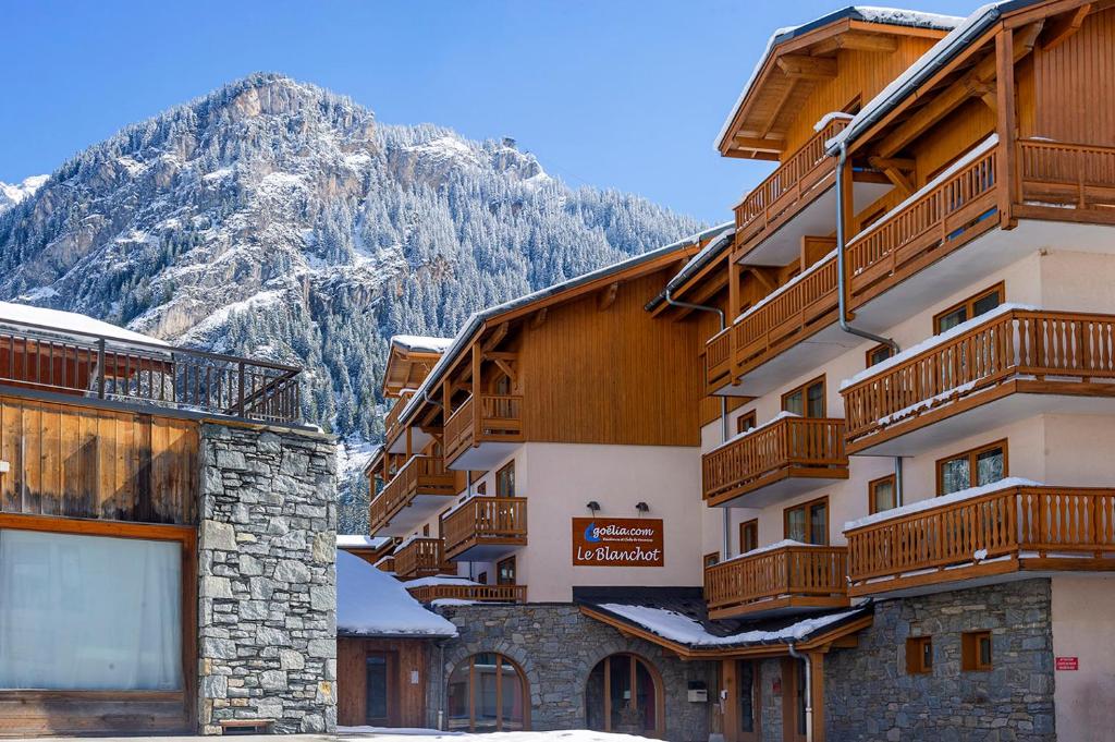 a building with wooden balconies and a mountain at Résidence Goélia Le Blanchot in Pralognan-la-Vanoise