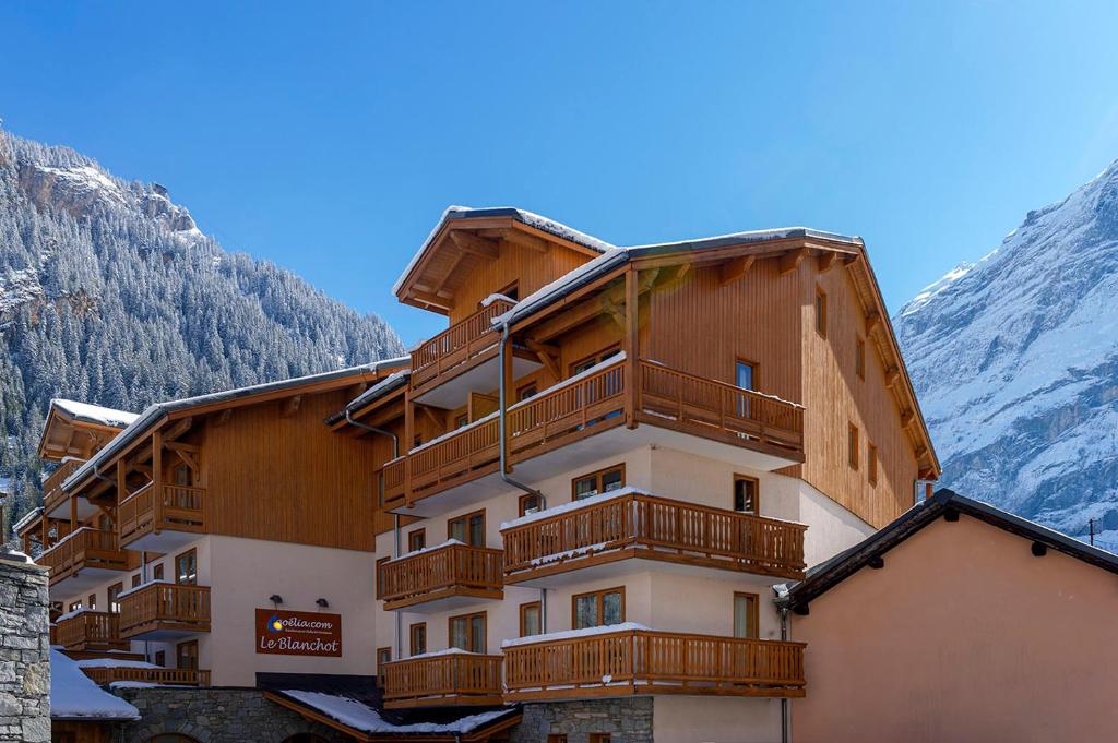 a building with wooden balconies on the side of a mountain at Résidence Goélia Le Blanchot in Pralognan-la-Vanoise