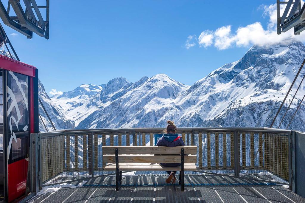 a woman sitting on a bench looking at the mountains at Résidence Goélia Le Blanchot in Pralognan-la-Vanoise