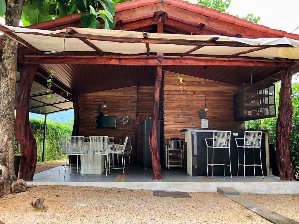 a wooden pavilion with chairs and a table and a kitchen at Cabaña Puerto Carrillo (Santa Marta) in Hojancha