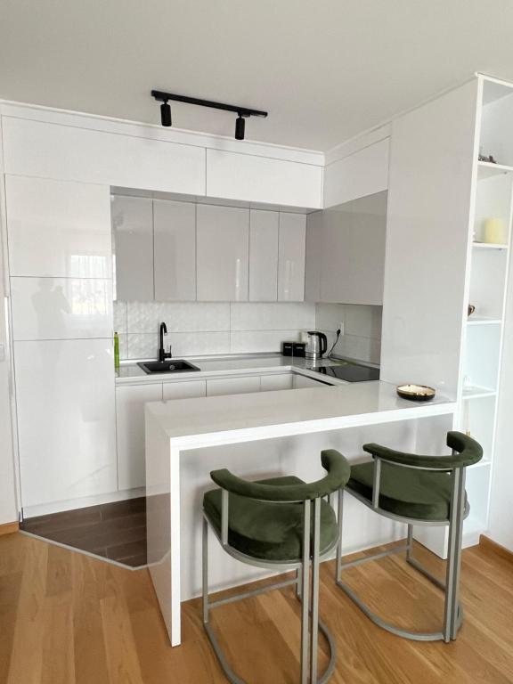 uma cozinha com armários brancos e cadeiras verdes em Apartman 306 em Lukavica