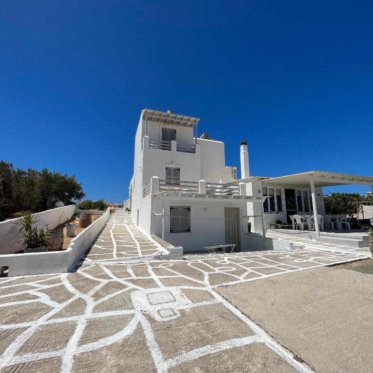 a white house with a stone walkway in front of it at Panagiotis Rooms in Naousa