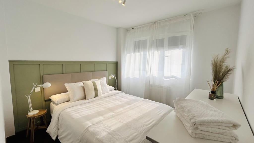 Habitación blanca con cama y ventana en Atico Duplex con terraza en Santander, en Santa Cruz de Bezana