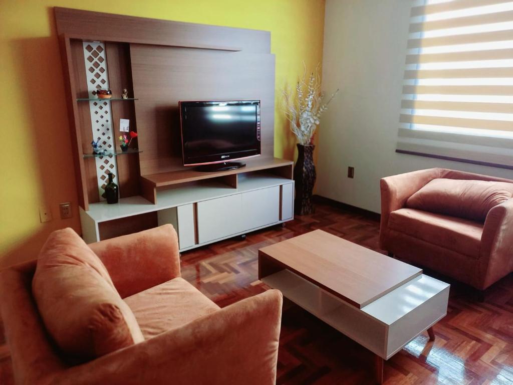 a living room with two chairs and a flat screen tv at BaspisDepar in Sucre