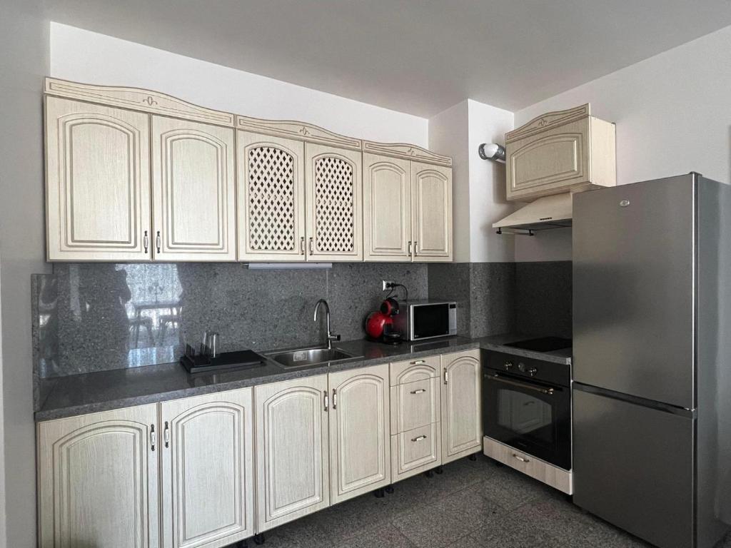 uma cozinha com armários brancos e um frigorífico de aço inoxidável em Апартамент за гости “Диана” em Burgas