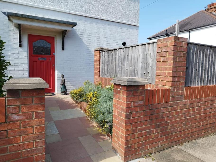 eine Backsteinmauer mit einer roten Tür vor einem Gebäude in der Unterkunft Cosy Modern Grimsby Home in Great Coates