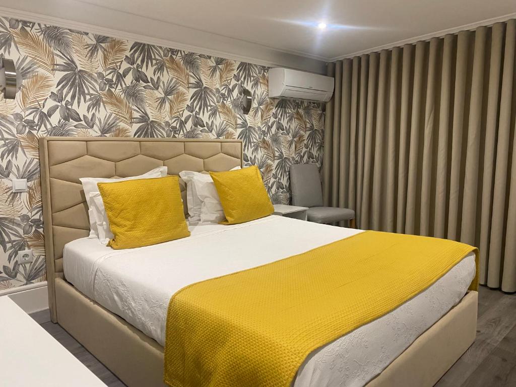 1 dormitorio con 1 cama grande con almohadas amarillas en GuestHouse Marquês, en Oporto