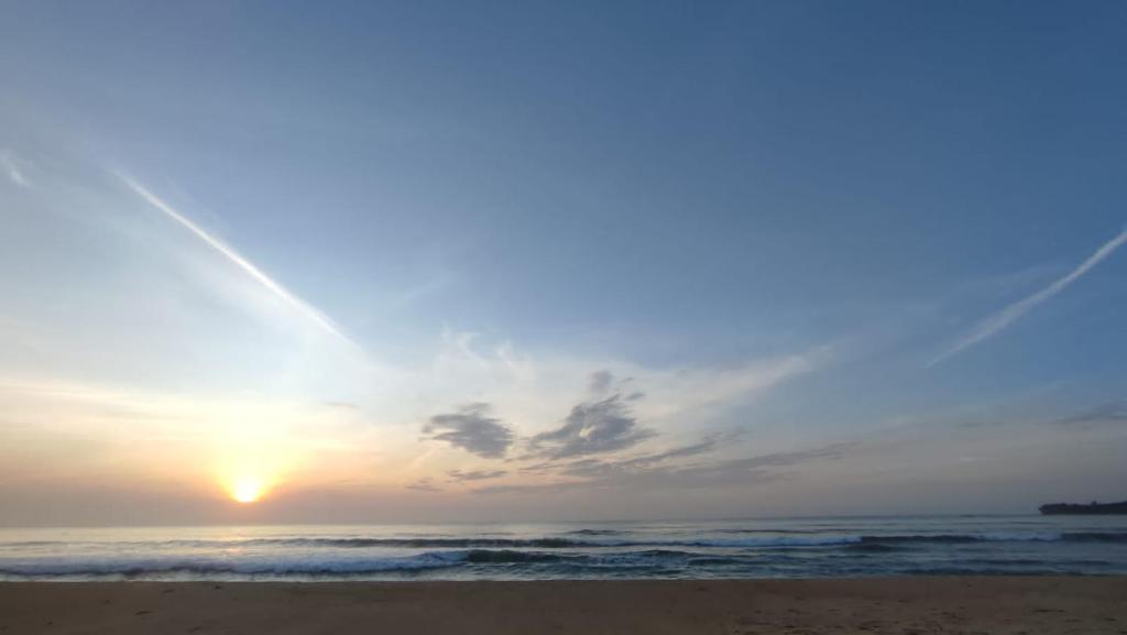 un tramonto su una spiaggia con l'oceano di Hotel arugambay beach inn resort ad Arugam