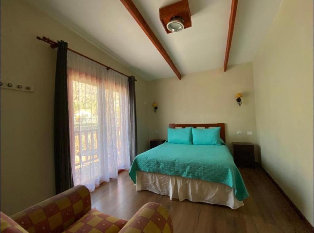 a bedroom with a bed and a couch and a window at Cabaña y Depto Puclaro in Vicuña