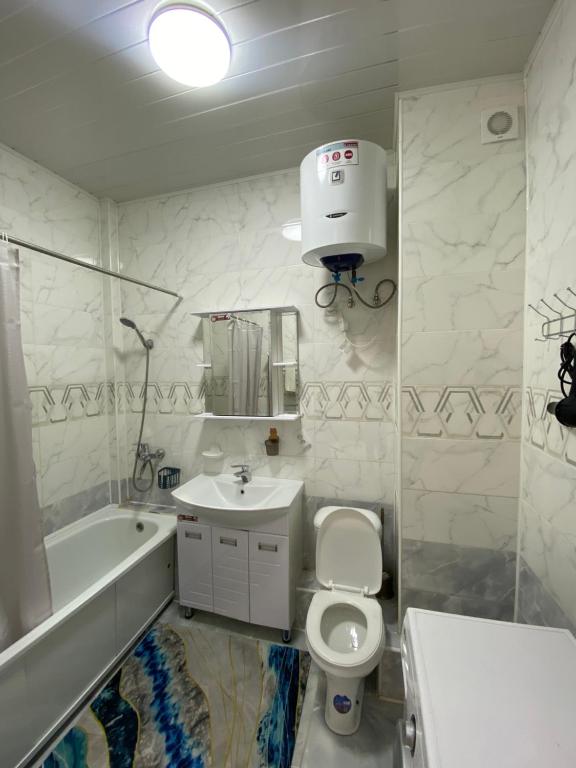 a white bathroom with a toilet and a sink at Elizavetta in Bishkek