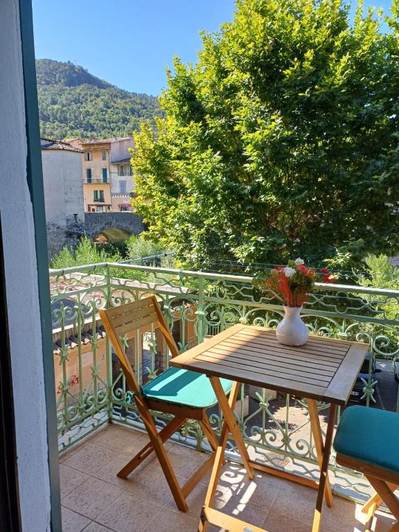 une table et des chaises sur un balcon avec un vase de fleurs dans l'établissement Riverside apartment, à Sospel