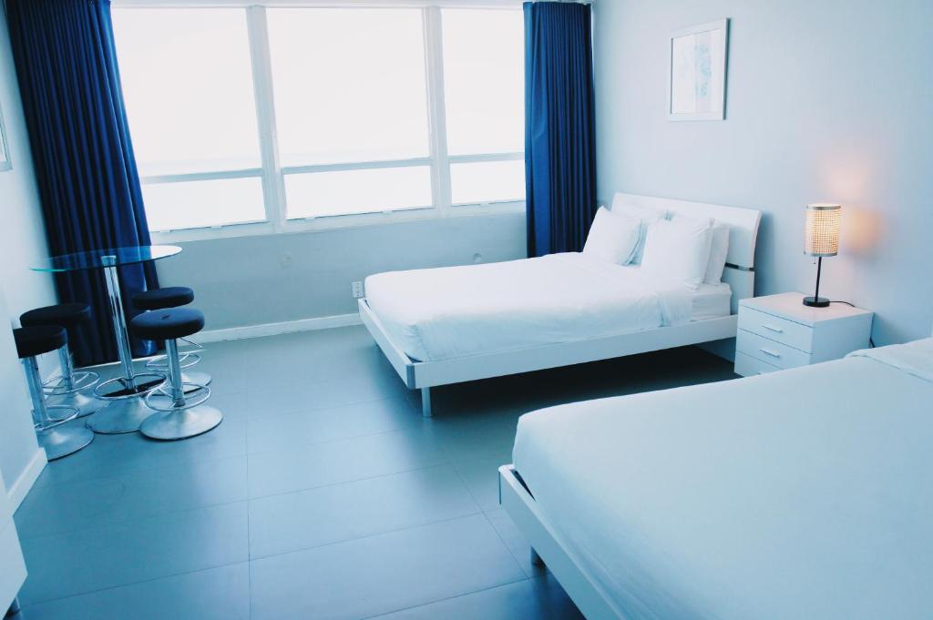 a white bedroom with two beds and a window at Castle 835 Oceanview studio on beach with pool, gym, bars, and FREE Parking in Miami Beach