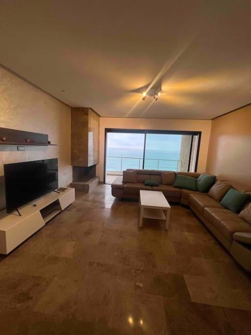 a large living room with a couch and a tv at Appartements lux respectueux in Sidi Bouqnadel