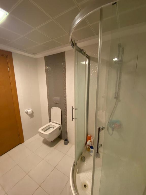 a bathroom with a toilet and a glass shower at Bornova nezih ferah Yıllık-Aylık_Haftalık in Burunabat