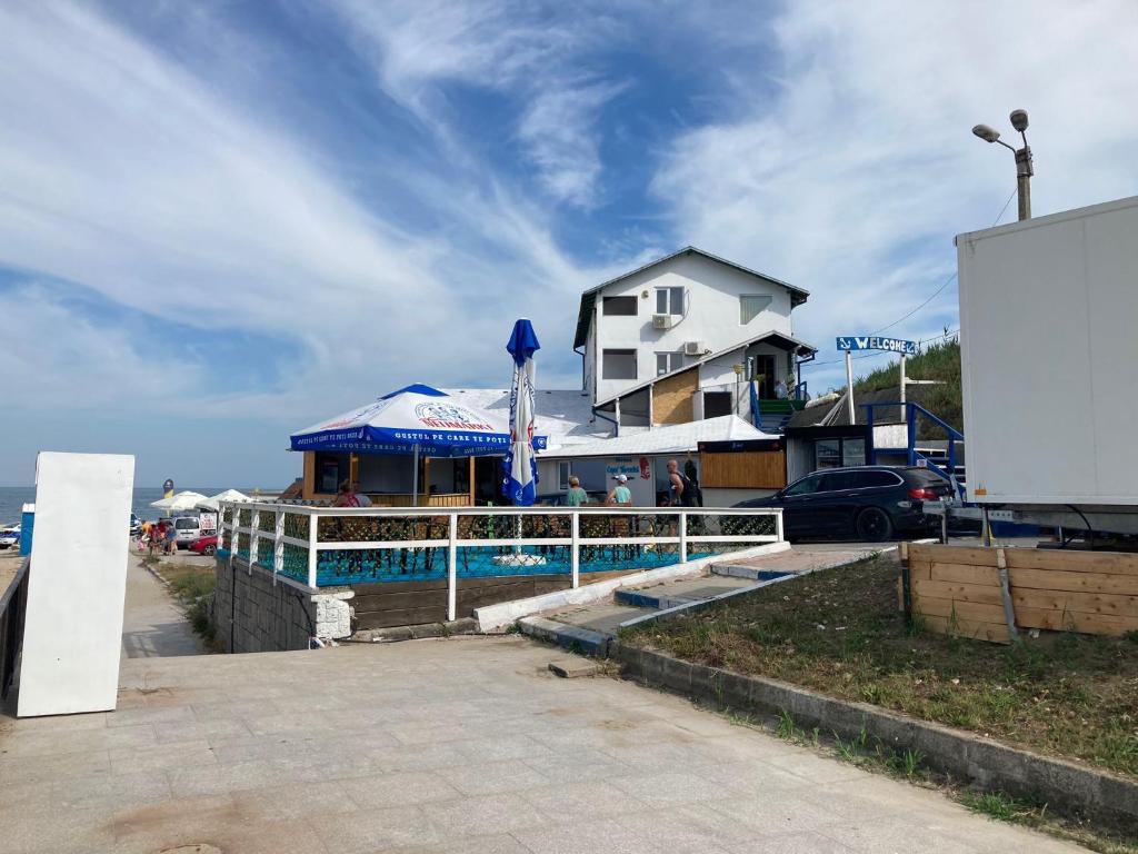 a building with a blue umbrella next to a pool at Hotel Capu' Turcului in Eforie Sud