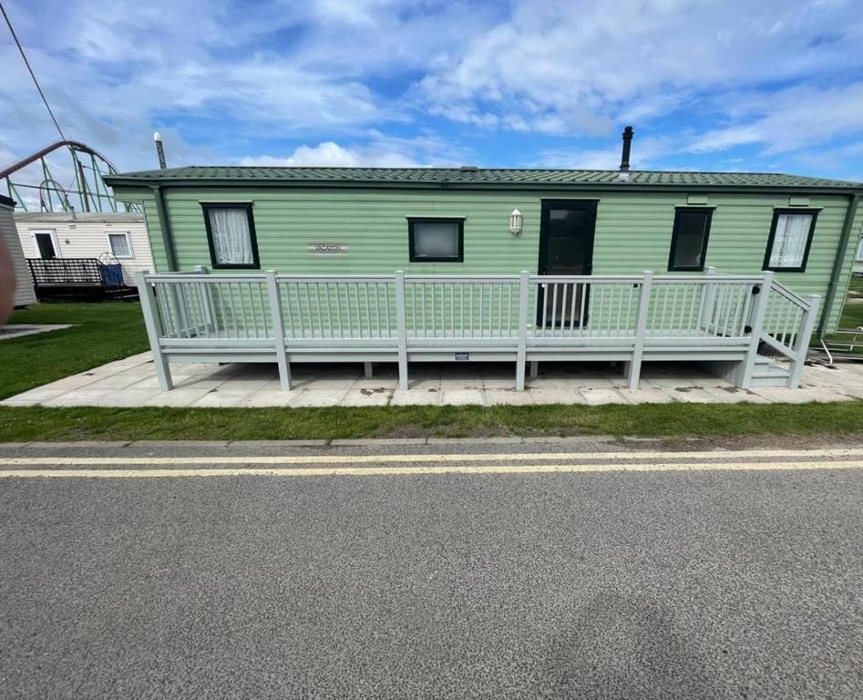 uma casa verde com um alpendre e uma montanha-russa em Fantasy Island, Sunnymede 8 Berth em Ingoldmells