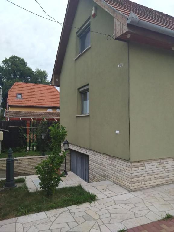 una casa verde con un edificio en Tókert Apartman, en Ráckeve