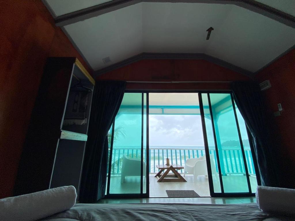 a bedroom with a large glass window with a view of the ocean at Pondok Beach Shack in Tioman Island
