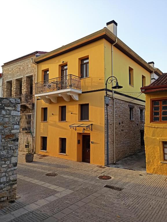 un bâtiment jaune avec un balcon dans une rue dans l'établissement To Agioklima, à Ioannina