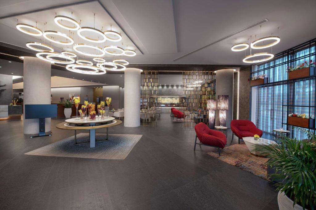 a lobby with red chairs and a table and a chandelier at Hilton Beirut Downtown in Beirut