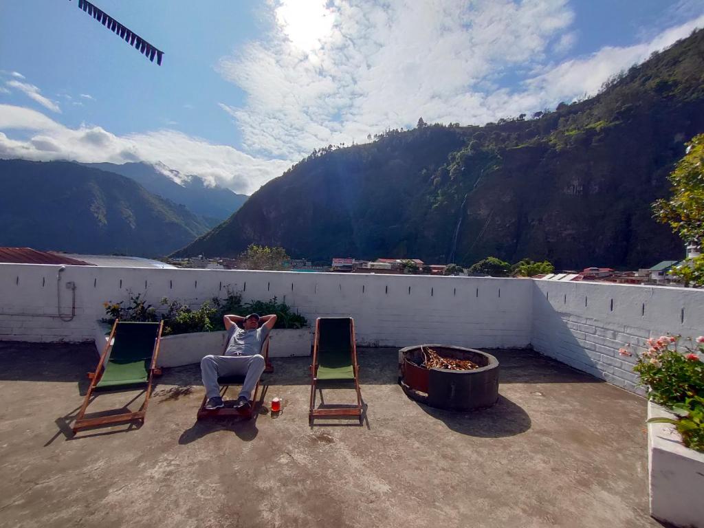 two chairs on a patio with a view of a mountain at Hostel Plantas y Blanco in Baños